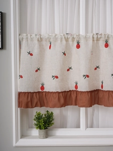 Detail of cream linen cafe curtain with red pineapple embroidery and brown ruffle trim