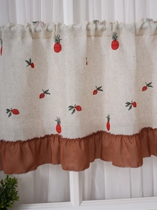 Detail of linen cafe curtain featuring fruit embroidery and caramel ruffled hem edge