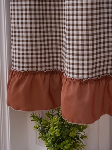 Detail of coffee brown checkered short curtain with solid ruffle edge for cabinet decor