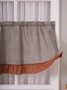 Detail of brown and white gingham cafe curtain with decorative ruffled edge hem