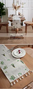 Detail of linen table runner featuring green cactus embroidery and white tassel fringe