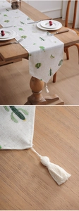 Detailed close-up of cactus embroidery and white tassel on linen table runner