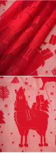 Macro detail of red Christmas mesh lace fabric with embroidered alpaca and tree patterns