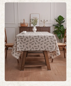 Detail of leaf pattern tablecloth with fringe edges on rectangular wood dining table