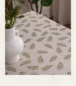 Detail of linen tablecloth featuring green leaf patterns and natural fiber texture