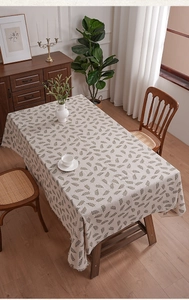 Detail of linen tablecloth featuring green leaf patterns and elegant tassel fringe edges