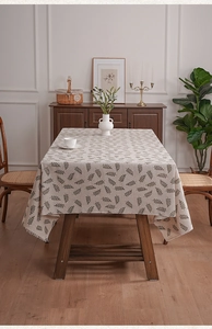Detailed view of rectangle tablecloth with green leaf patterns and elegant tassel edge