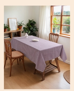 Purple and white gingham checkered tablecloth on a wooden table in a sunny room