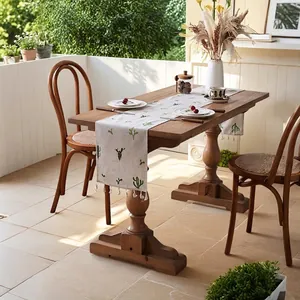 Linen table runner with green cactus embroidery and white tassels on a wooden dining table