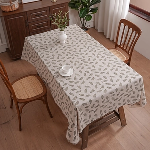 Linen cotton tablecloth with green leaf pattern and tassels on a wooden dining table