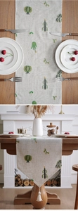 Detail of linen table runner with green cactus embroidery and cream tassel decor