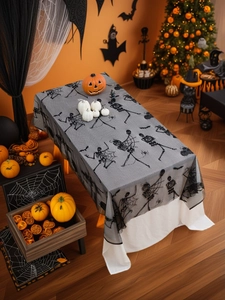 Close-up of black lace Halloween tablecloth with dancing skeletons and spiderweb patterns