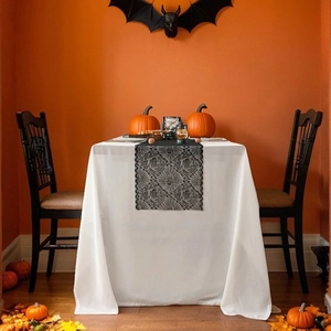 Halloween black lace spider web table runner set over white tablecloth with pumpkin decor