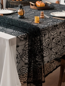 Close-up of black lace spider web tablecloth showing intricate weaving and spider patterns
