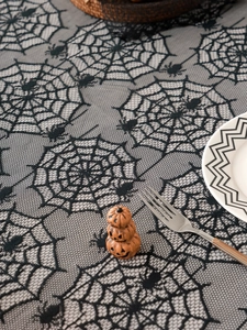 Detail view of black lace Halloween tablecloth featuring cobweb and spider patterns