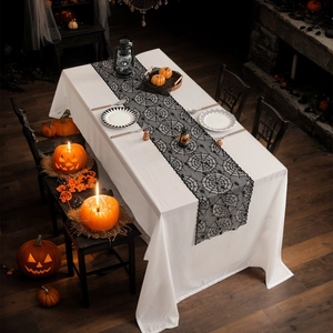 Halloween tafelloper van zwart kant met spinnenwebpatroon op een wit rechthoekig kleed