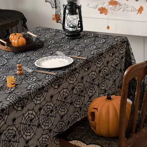 Black lace spider web tablecloth for Halloween party decor over a wooden dining table