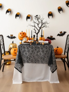 Detailed close-up of Halloween black lace tablecloth with spider web pattern on white base