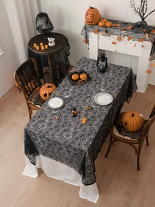 Close-up of black lace spider web tablecloth with detailed festive indoor holiday decor