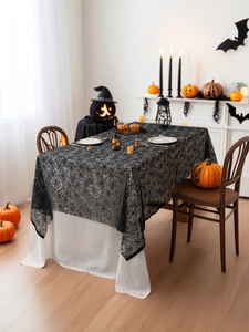 Detail of black lace spider web tablecloth with festive Halloween pumpkin decorations