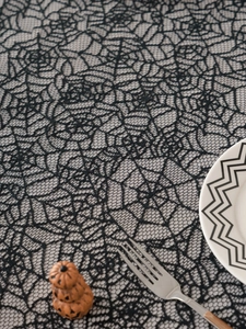 Detail of black lace spider web tablecloth with rose patterns for Halloween table decor
