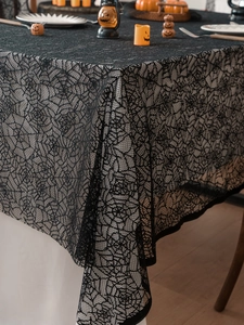 Close-up of black lace Halloween tablecloth featuring detailed spider web patterns on a table