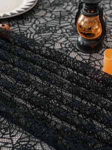 Macro shot of black lace table runner featuring an intricate spider web pattern for Halloween