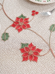 Dettaglio ravvicinato del ricamo di poinsettia rossa su tovaglia natalizia beige