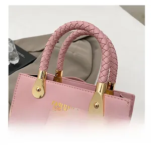Detail der rosa PU-Lederhandtasche mit gewebtem Griff und goldenen Metallbeschlägen