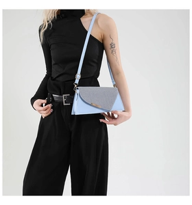 Détail du sac bandoulière en cuir bleu clair avec rabat pailleté argenté et boucles dorées