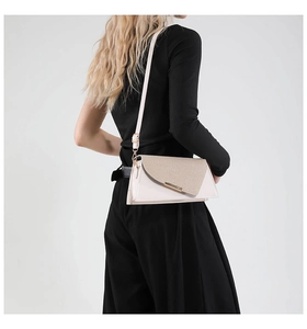 Détail du sac bandoulière beige avec rabat tissé et fermoir métallique allongé