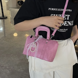 Pink PU leather crossbody pillow bag with lace bow and pearl charm shown on model
