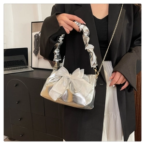 Close-up van zilveren geplooide handtas met een grote witte mesh strik en ketting