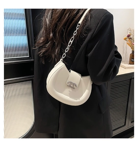 Details einer beigen Halbmondtasche mit silberner Logo-Schnalle und Metallkettenriemen