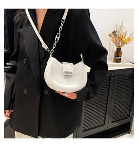 Detail der weißen halbmondförmigen Ledertasche mit silberner Kette an einem Blazer