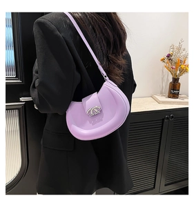 Detail der lila Halbmond-Tasche mit Silberschnalle auf einem schwarzen Blazer
