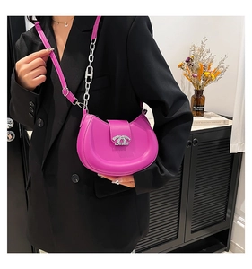 Detail der fuchsiafarbenen Halbmond-Tasche mit Silberkette auf schwarzem Blazer