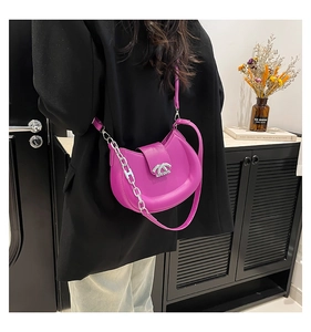 Detail der fuchsiafarbenen Halbmond-Tasche mit Metallkette und Logo-Schnalle am Trageriemen