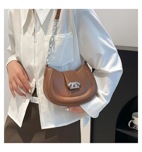 Modische karamellfarbene Halbmond-Tasche mit Silberkette, getragen von einem Modell