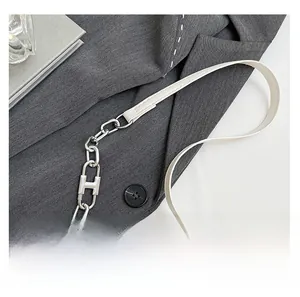 Nahaufnahme des weißen Lederriemens mit silberner H-Kette auf einem Damen-Blazer