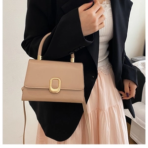 Détail du sac à main en cuir beige avec une boucle ovale dorée texturée et élégante