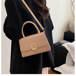 Detailed view of beige leather small square bag with elegant gold clasp on a model