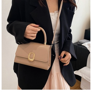 Détail du sac beige élégant avec grand fermoir ovale doré et texture de cuir fine