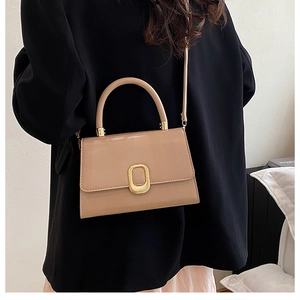 Détail du sac bandoulière beige avec boucle dorée ovale et poignée supérieure
