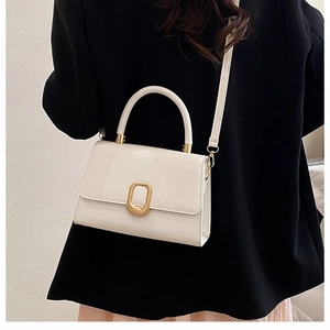 Petit sac carré blanc porté par un mannequin avec fermoir métallique doré élégant