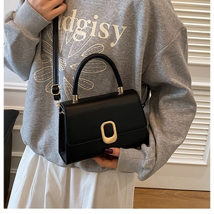 Détail d'un sac bandoulière en cuir noir avec fermoir doré et poignée supérieure