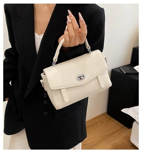 Vista detallada del bolso tipo cartero crema con elegante cierre giratorio de metal fino