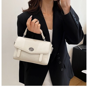 Detalle del bolso blanco roto con cierre giratorio plateado y textura de cuero sintético