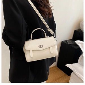 Modelo con bolso mensajero crema minimalista con cierre giratorio de plata y bandolera