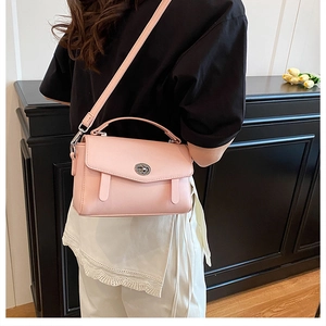 Detalle de bolso bandolera de cuero rosa con cierre giratorio plateado y asa superior